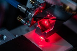 A Rice University lab tests material covered in strain-sensing smart skin. The multilayer coating contains carbon nanotubes that fluoresce when under strain, matching the strain experienced by the material underneath. (Credit: Jeff Fitlow/Rice University) 