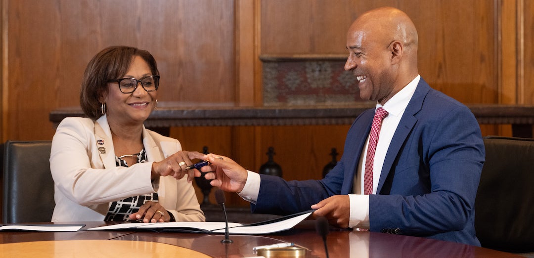 Vanessa Wyche, director of NASA’s Johnson Space Center, and Rice University President Reginald DesRoches pass the pen as they sign an extension of the Space Act Agreement that promises continued cooperation between the institutions. The signing ceremony took place at Rice’s historic Founder’s Room on Aug. 19. (Credit: Jeff Fitlow/Rice University)