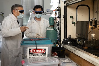 Rice University chemist James Tour, left, and postdoctoral research associate Bing Deng prepare to “flash” electronic waste to recover its valuable metals for recycling. The lab’s process, first developed to turn waste food and other carbon sources into graphene, has been adapted to recover other materials. Photo by  Jeff Fitlow
