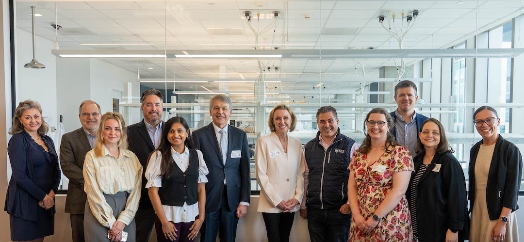a group of 12 people pose in front of a lab setting