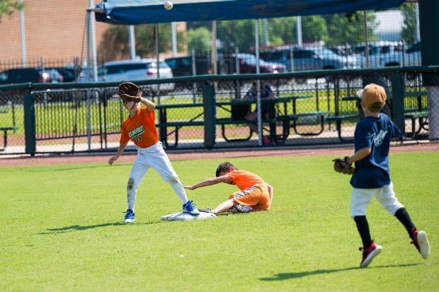Three children in a field playing baseball 