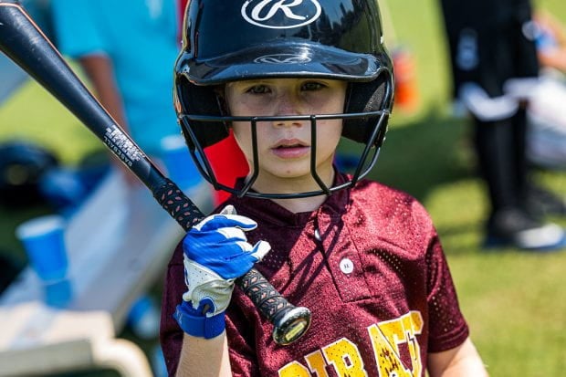 Boy holding baseball bat  with helmet on looking into camera