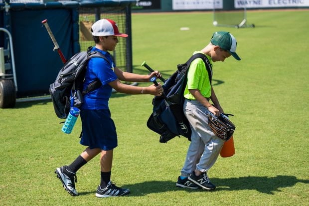 Two boys walking with baseball equipment. 