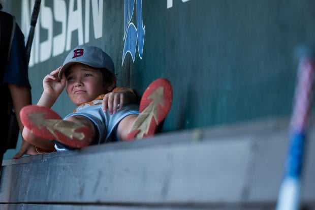Boy laying down in baseball dugout. 