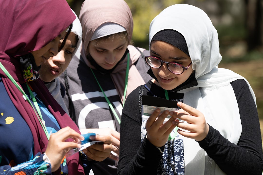 Young girls in head scarves huddle together at science festival