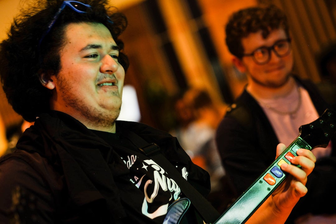 Close up picture of smiling student playing Guitar Hero game