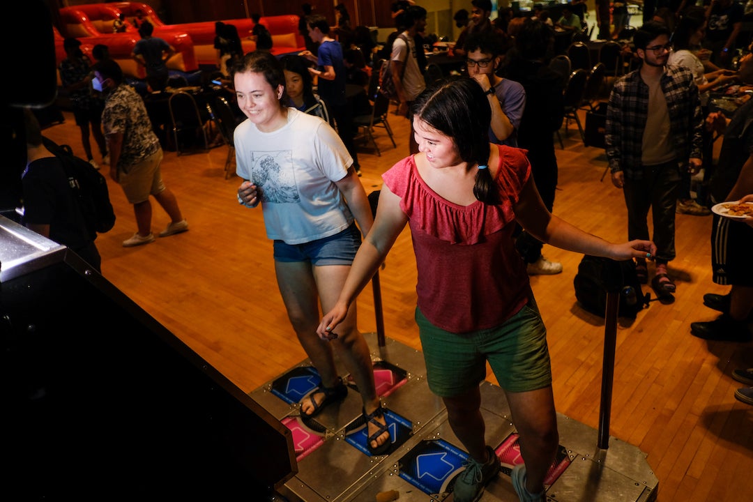 Two students playing Dance Dance Revolution arcade game