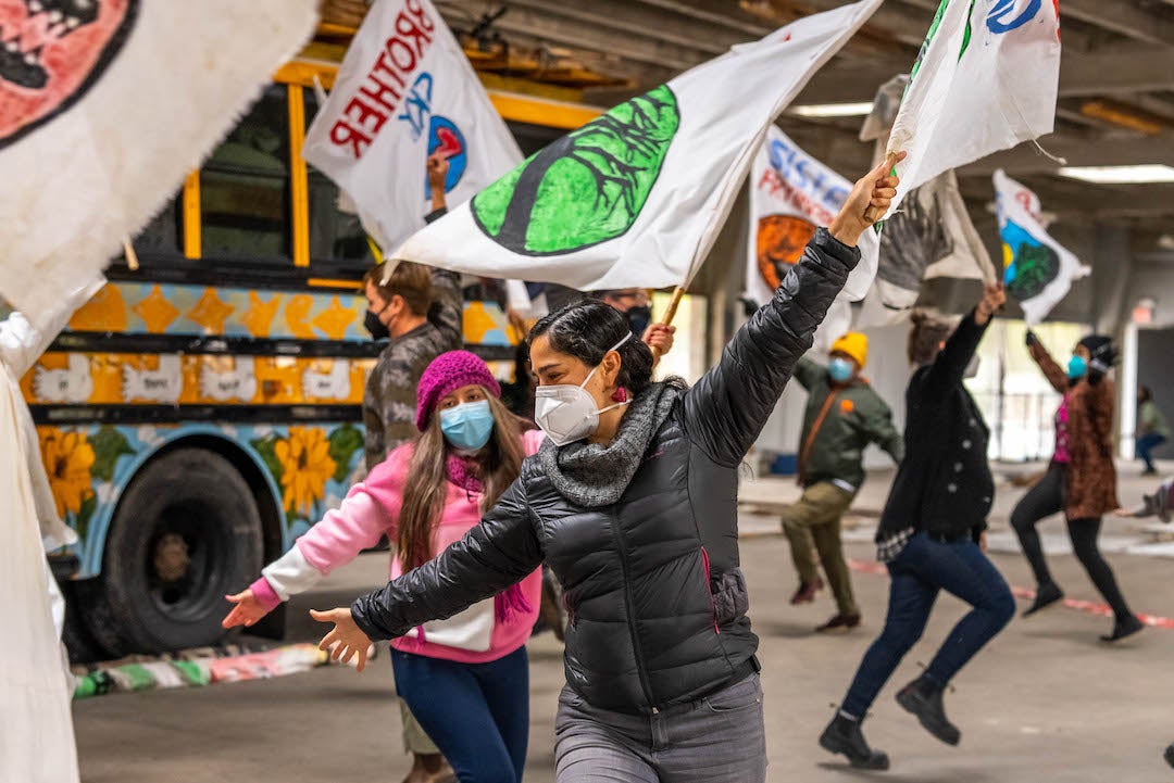 Pre-performance practice at Bread and Puppet workshop with performers brandishing flags