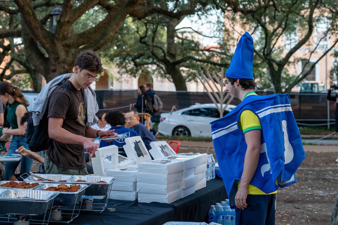 students getting free food at pre-Hanukkah event including one person in a dreidel costume