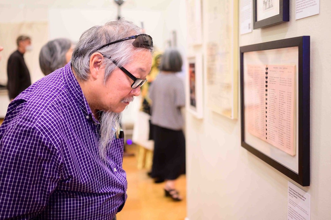 Man looks at historic documents in Houston Asian American Archive exhibition