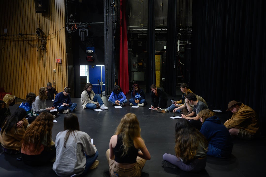 Students and professional actors in circle on stage during workshop