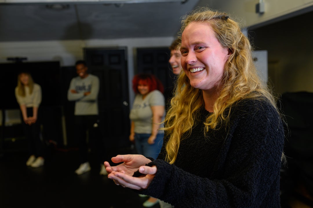 Woman smiles during acting exercise with palms outstretched