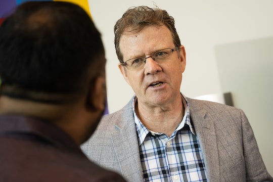 Colm Kelleher speaks with attendees of the conference during a reception period between sessions.