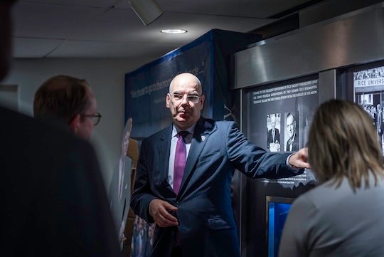 A man stands in front of a wall of images, explaining them to a small audience