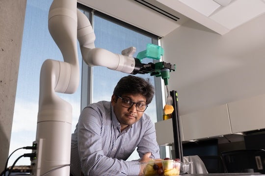 researcher posing with robotic arm
