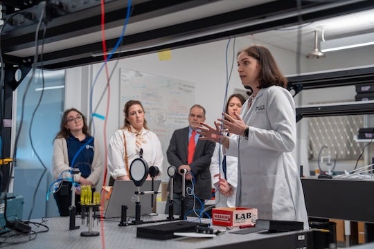 female researcher in lab coat presenting to a group