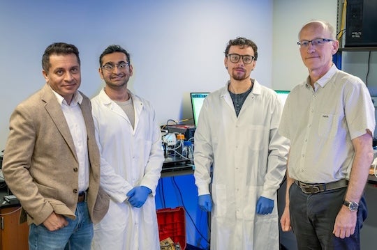 four men stand in a lab setting looking at the camera