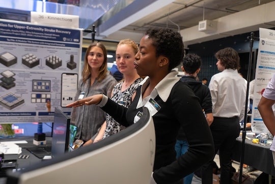 Member of team TacTile explain their project in front of a poster