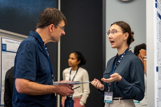 Thomas Killian, dean of the Wiess School of Natural Sciences, listens as a student presents research during the Natural Sciences Undergraduate Research Symposium at Rice University.