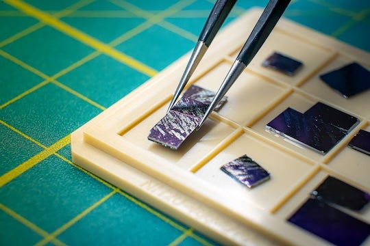 tweezers pick up a sample of material off of a tray