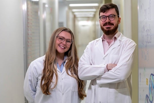 young researchers in lab coats smiling at camera