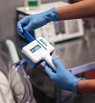 A nurse inserting a lateral flow cassette into the BiliDx jaundice test device