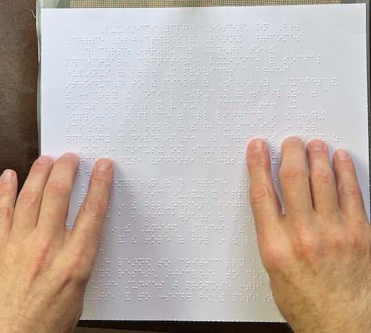 Robert Englebretson, associate professor of linguistics at Rice University, reads a page of braille.