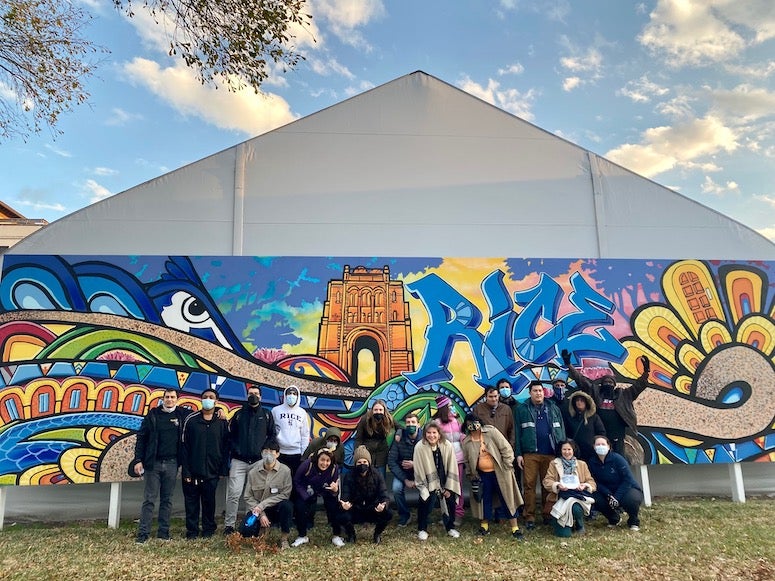 Young adults in the GREAT project pose in front of a Rice mural.