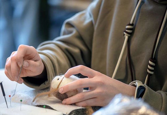 Close up of person making felted art charm