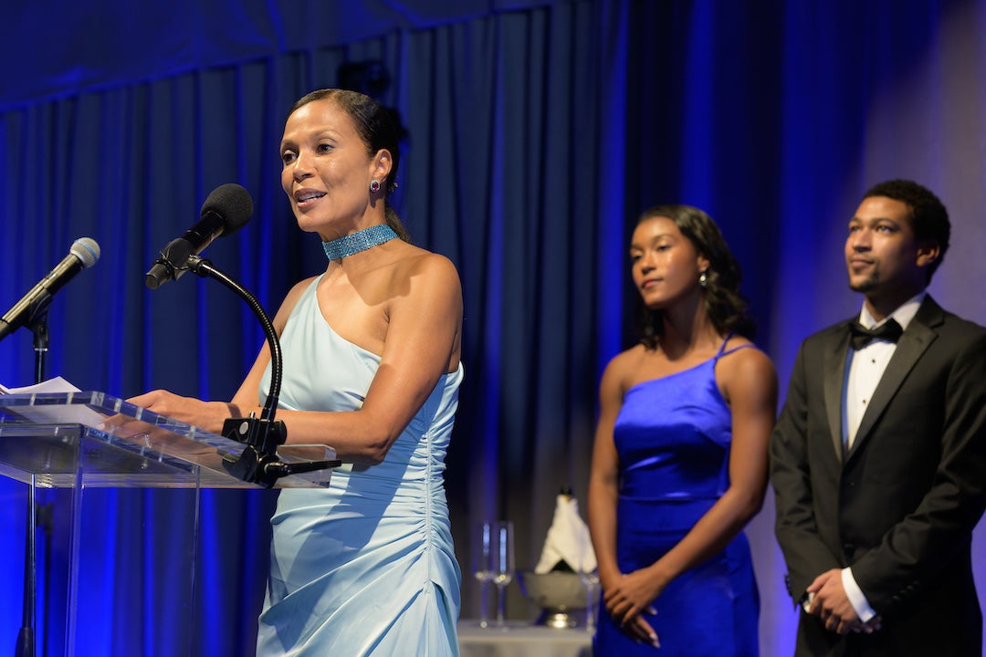 Paula Gilmer DesRoches speaks to gala attendees while two of her children look on.