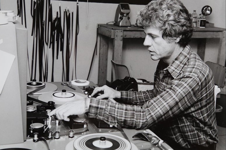 Photo of James Blue seated, editing film by hand, circa 1978