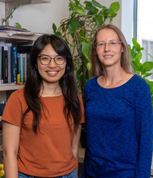 An Asian woman stands next to a white woman. They are both smiling. 