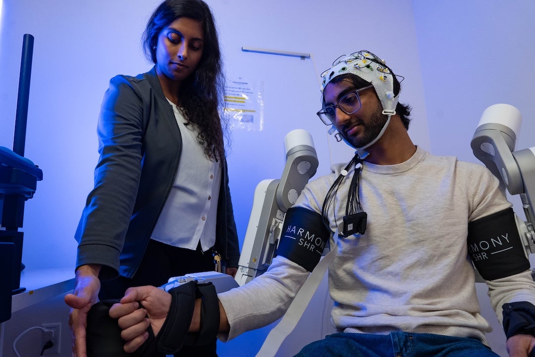 Keya Ghonasgi and Snehil Mathur, a graduate student in Mechanical Engineering, demonstrating how the exoskeleton functions 