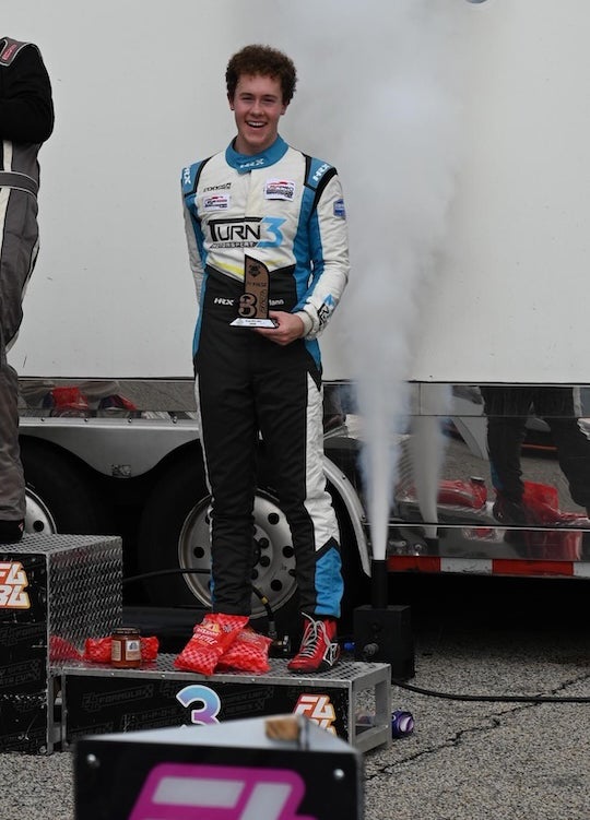 Luke Mann stands on the podium at the inaugural Collegiate Racing Series race at Michelin Raceway Road Atlanta in 2026.