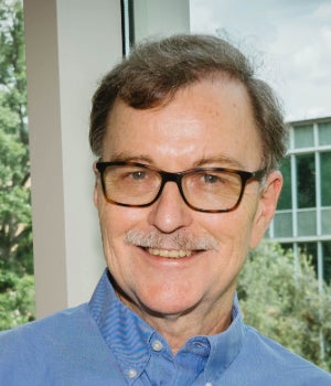 An older white man smiles at the camera