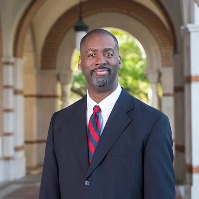 A black man in a suit smiles at the camera