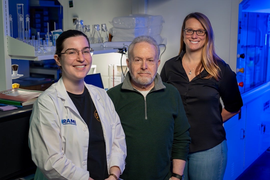 A woman, a man, and another woman standing in a lab smiling at the camera