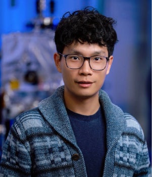 An Asian man smiles slightly at the camera