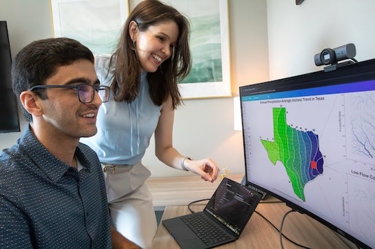A woman and man look at a computer screen showing average rainfall across Texas