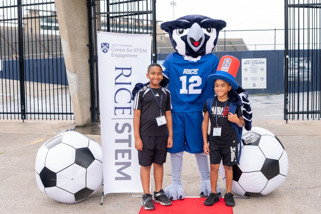 Two campers stand next to Sammy the owl in front of Rice Stadium