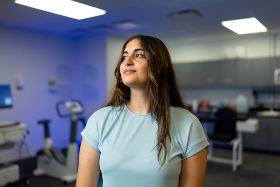 A Latina woman with long wavy brown hair looks upwards with a slight smile.