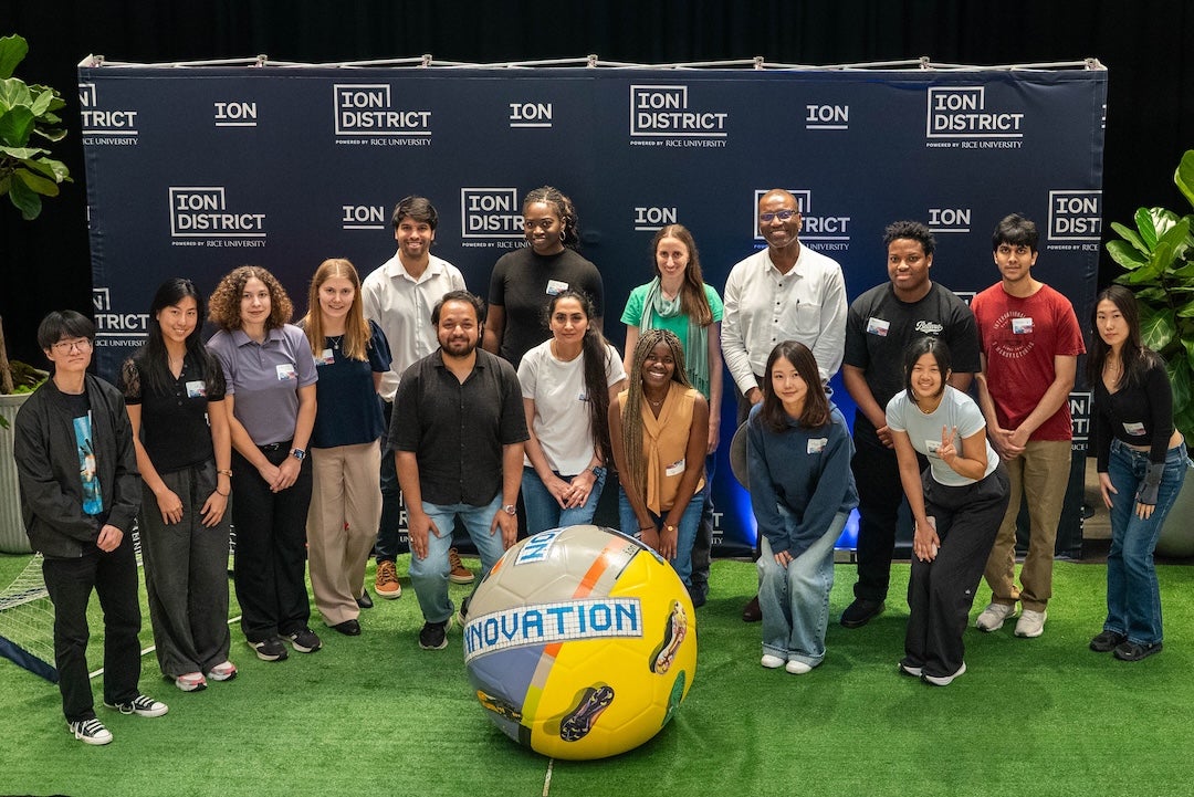 A group of people gather around a large soccer ball. 