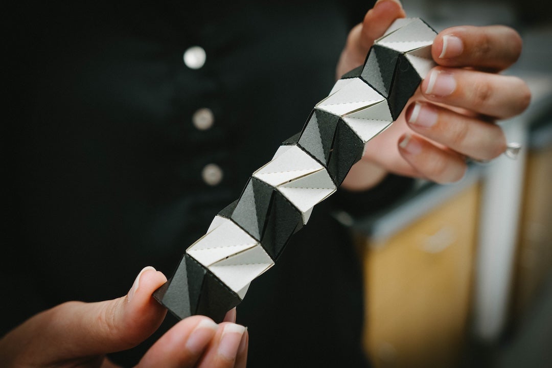 Novelino holds an origami structure.