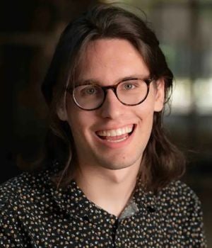 A young white man smiles at the camera