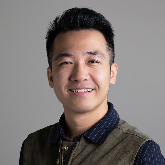 An Asian man smiles at the camera