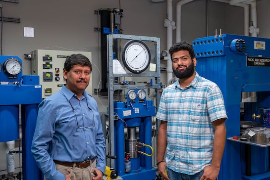 Two men standing next to each other in a lab. 