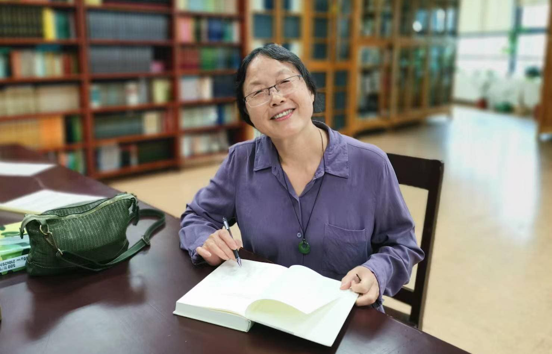 Nanxiu Qian smiling at desk