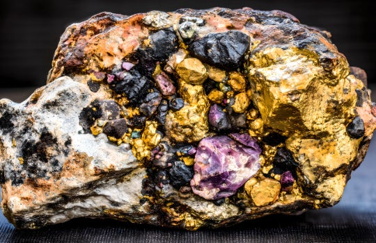 Raw rare earth mineral crystals on the weathered crust of yellow brown granite