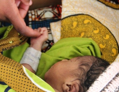 Caregiver touching newborn baby's hand