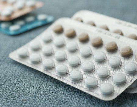 Stock Image: birth control pills on wooden background.